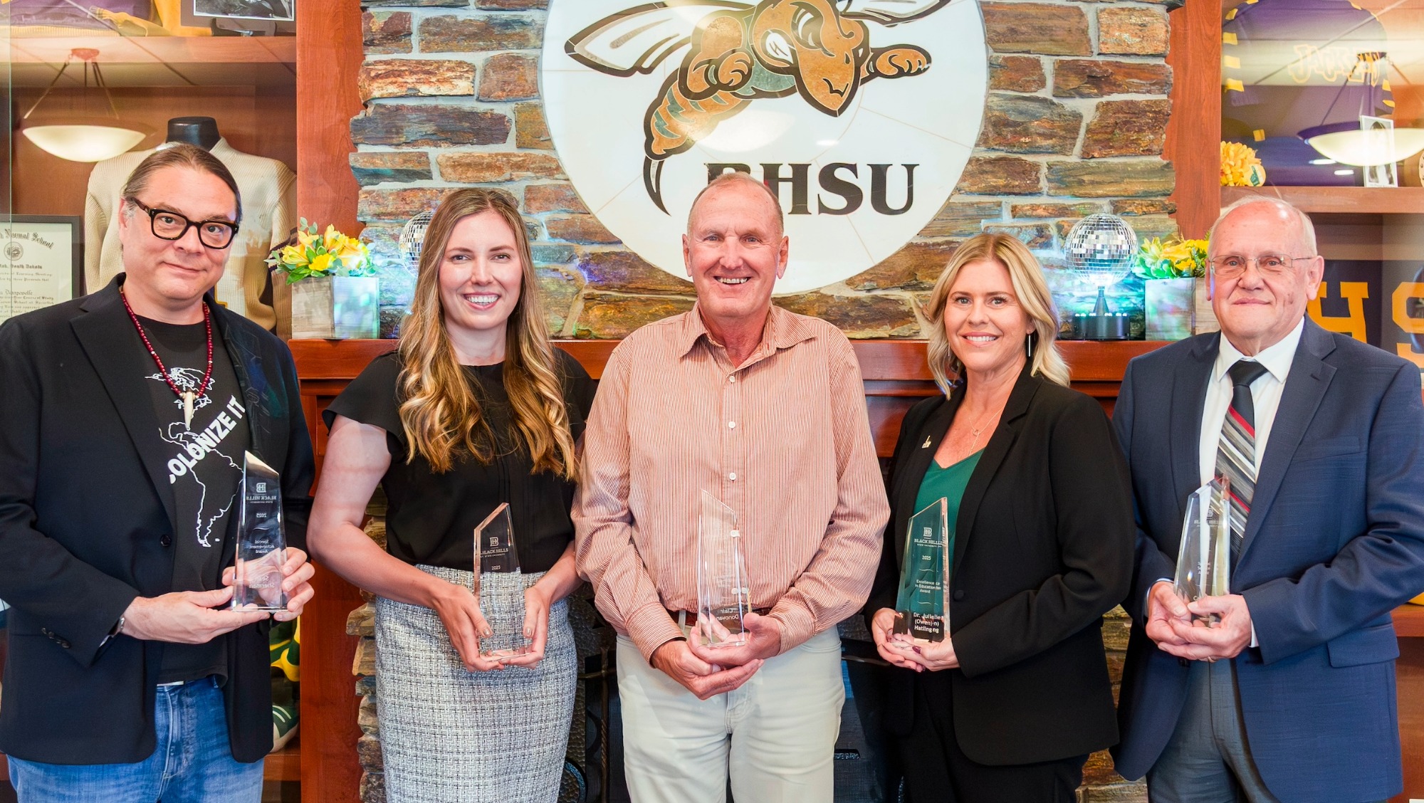 Five alumni hold their awards and smile