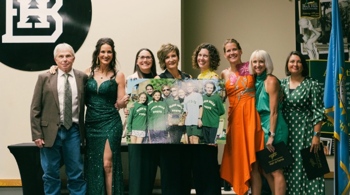 The 1999 women's cross country team holds a picture and smiles