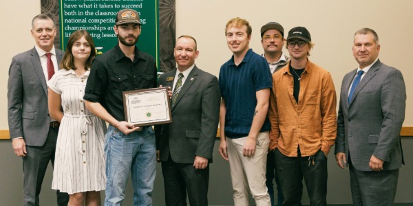 Eight people smile and hold a certificate awarded to PONDER