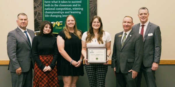 Six people smile and hold a certificate awarded to Shutter Buzz 