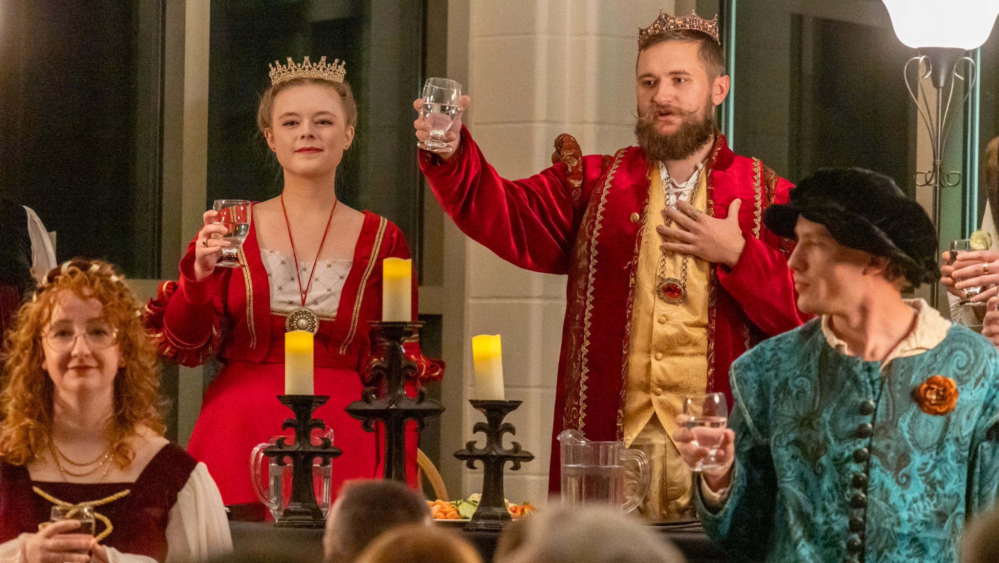 A king and queen at the Madrigal Dinner lift their glasses in a toast