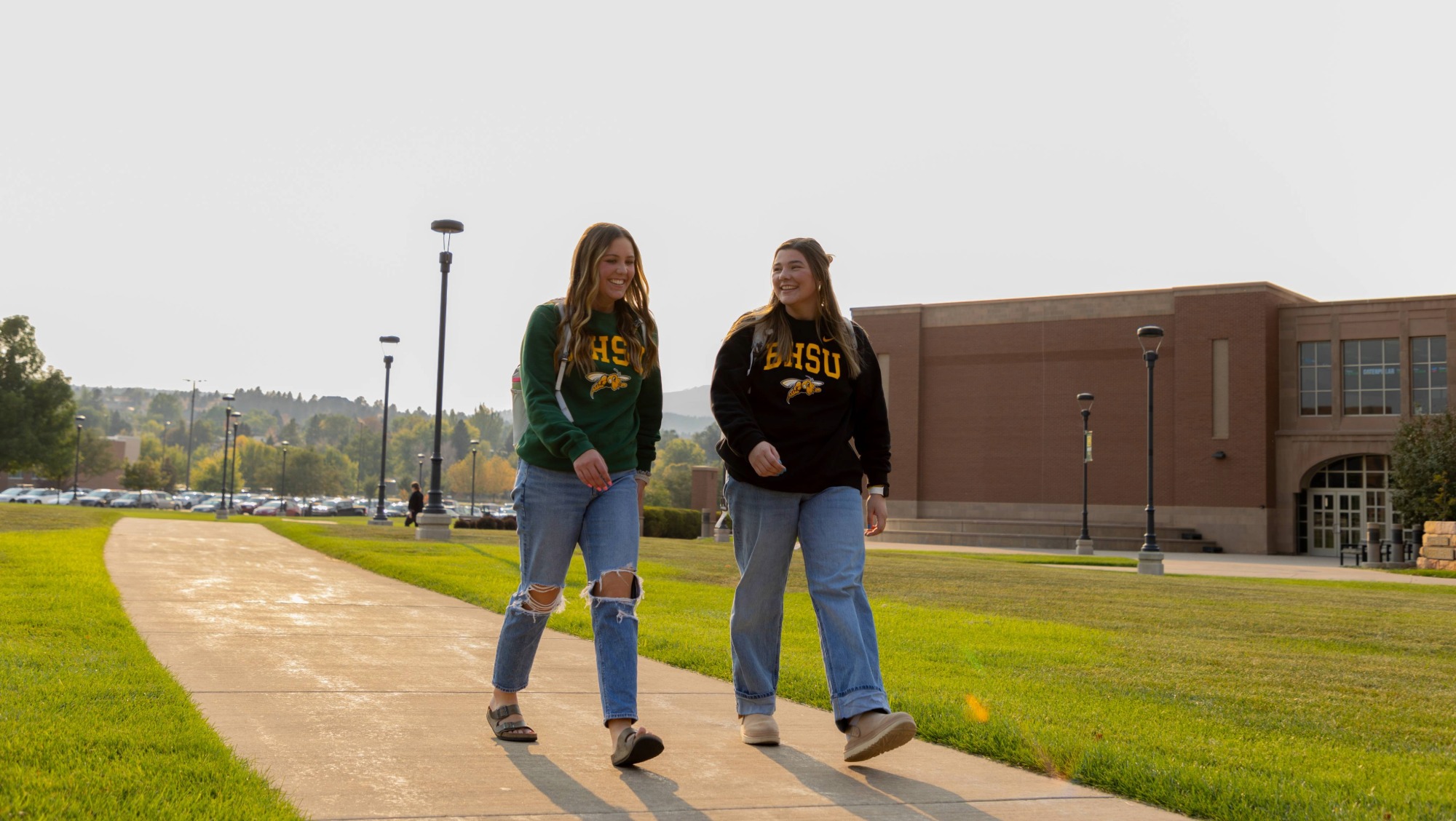 two girls walk on campus together while having conversation
