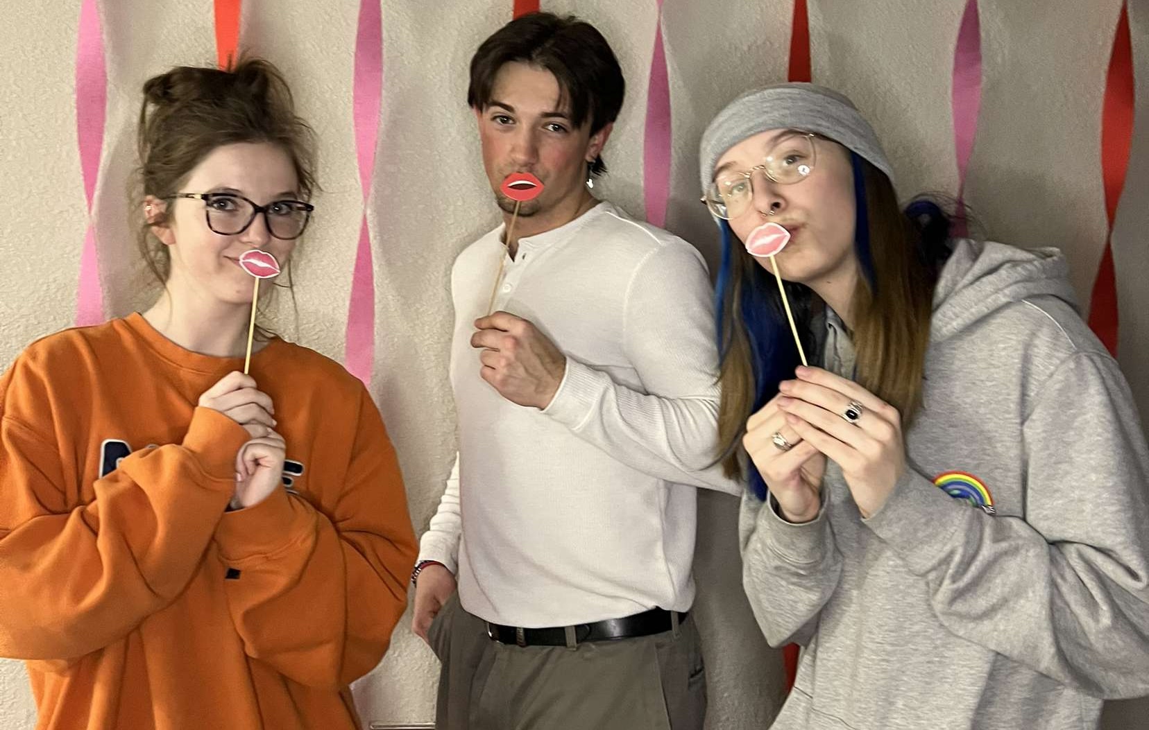3 students holding up valentines lips on sticks to their mouths for a little fun at an All Hall event in the residence halls.