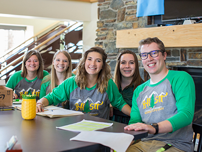 Five RAs pose for a photo at the front desk in Bordeaux Hall.