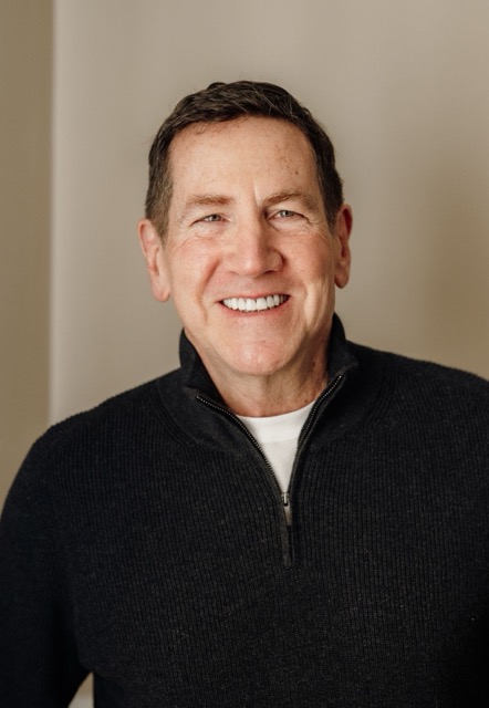 Headshot of Dan Gardner, a smiling man with short hair wearing a dark sweater, posed against a neutral background.