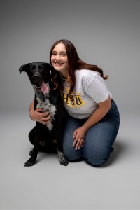 torrance-brown Graduate Torrance Brown kneels next to a dog while smiling for a photo
